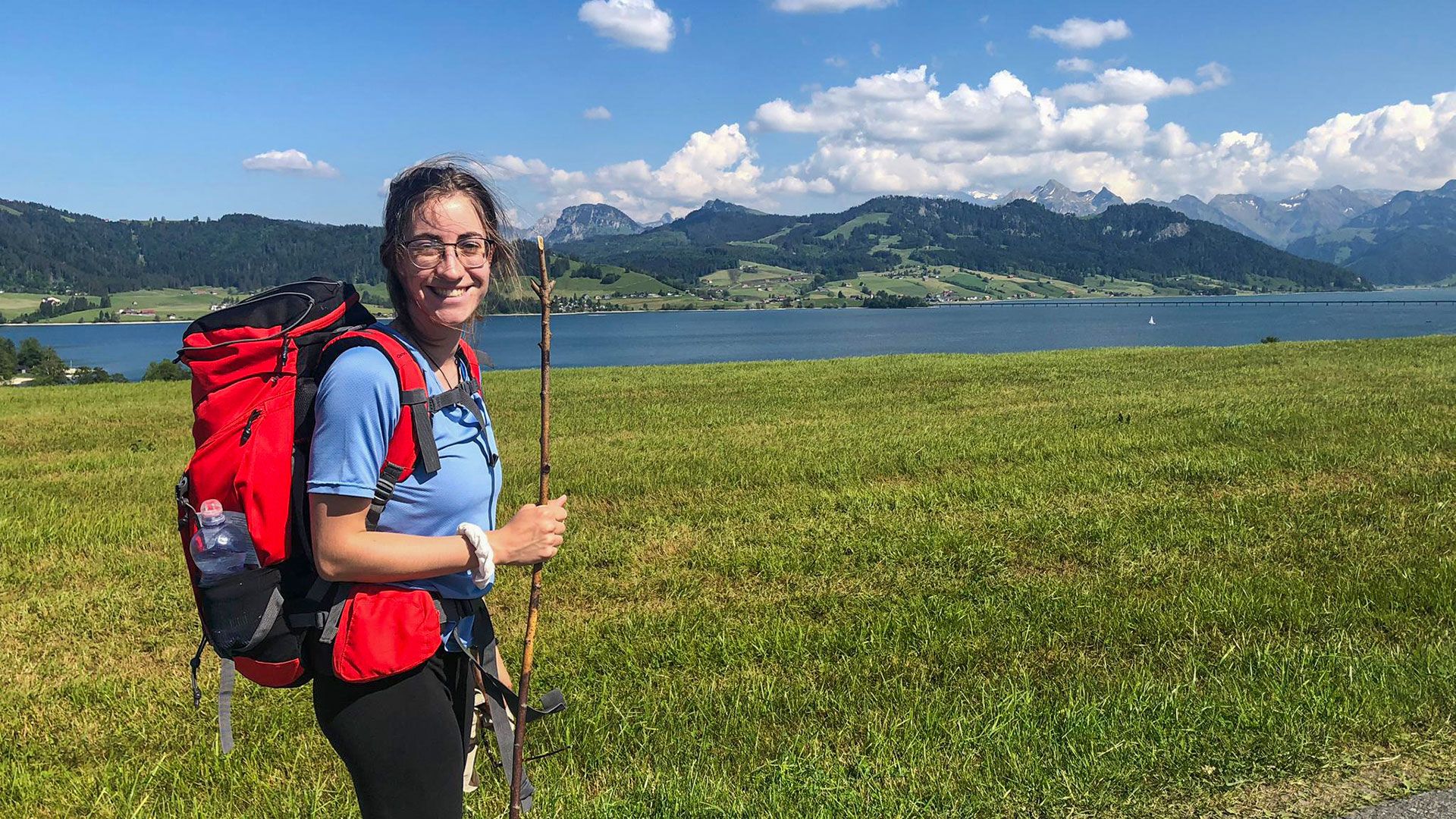 Frau mit Wanderrucksack vor Schweizer Bergkulisse.