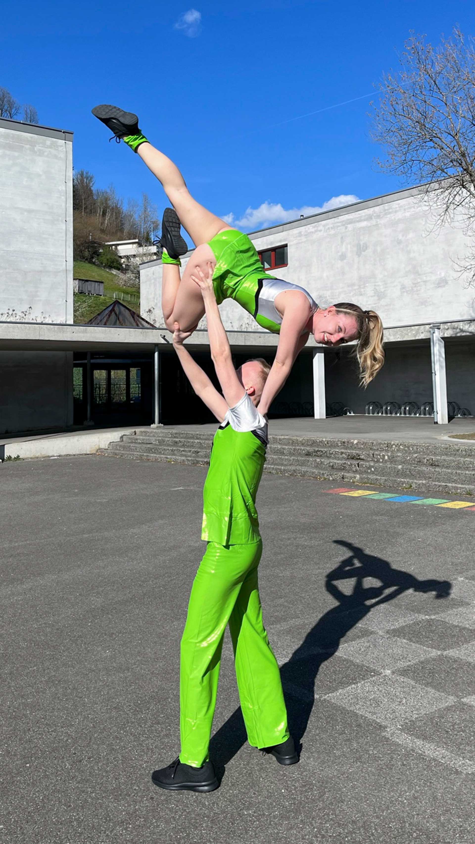 Figure de danse: un homme soulève sa partenaire et la soutient en tenant sa jambe droite, pliée, avec ses deux mains. Tête en bas, elle s’appuie de ses deux mains sur ses épaules et étend sa jambe gauche.